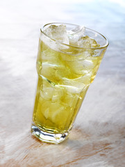 Gold drink with ice. Photographed on a light wooden background. Light illumination.
