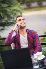 Young man sitting in a cafe on a coffee break. using phone