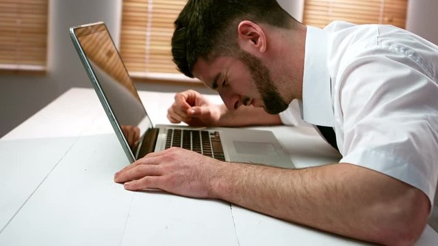 Tired businessman sleeping on laptop at desk