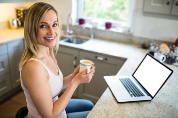 Pretty blonde woman having coffee and using laptop