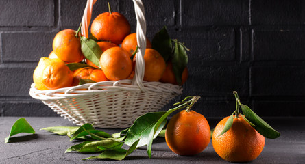 White basket with tangerines on a black background, horizontal, selective focus