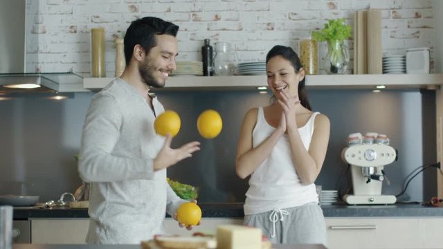 Slow Motion of a Guy Impressing His Lady with Juggling Oranges on the Kitchen. Shot on RED Cinema Camera in 4K (UHD).