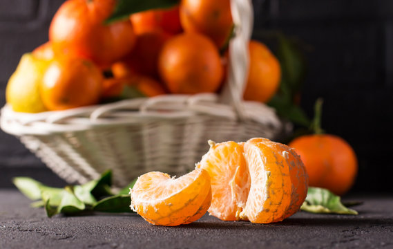 White basket with tangerines on a black background, horizontal vertical, selective focus
