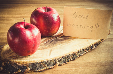 Organic apples and Good morning note on rustic wooden background.