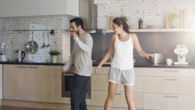  Happy Couple Creatively Dances in the Kitchen. Both are Adorable and Smiling. Shot on RED Cinema Camera in 4K (UHD).