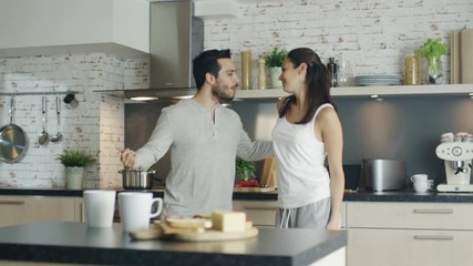  Happy Young Couple Dances in the Kitchen and then Embracing