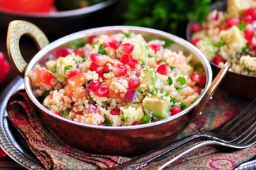 Healthy salad with couscous, tomato, avocado, red onion, pomegranate and olive oil. Eastern cuisine.