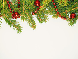 New Year background. Red balls toys and beads on a spruce. Decorated Green Christmas fir tree on white.