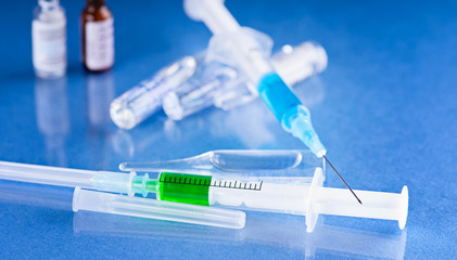 Medical vials for injection with a syringe isolated on blue background.