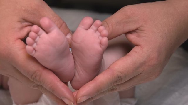 Baby's legs in the hand of an adult