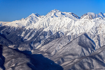 Beautiful mountain winter scenery of the Main Caucasian ridge with snowy peaks on blue sky background