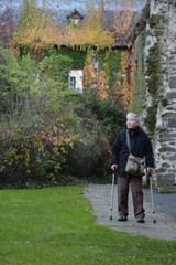 Fototapeta na wymiar eine ältere frau mit krücken geht in der ruine der klosterkirche arnsburg