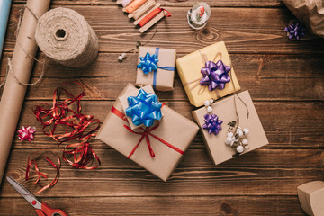 From above view of small wrapped presents decorated with colorful ribbons on wooden desk. 