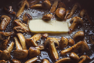 Button mushrooms roasted in a butter in a hot black frying pan