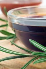Soy sauce in a glass and a sprig of rosemary
