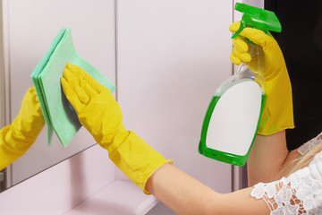 Female hands cleaning mirror with green cloth. Spring clean up