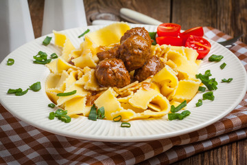 Tagliatelle, meatballs in dark sauce and tomato.