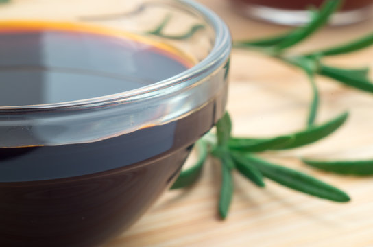 Glass dish with soy sauce and rosemary sprigs
