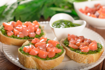 Bruschetta with pieces of salmon and pesto sauce