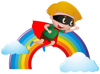 Boy dressed as hero flying over the rainbow