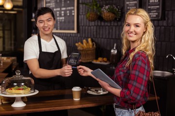 Smiling barista taking credit card from customer