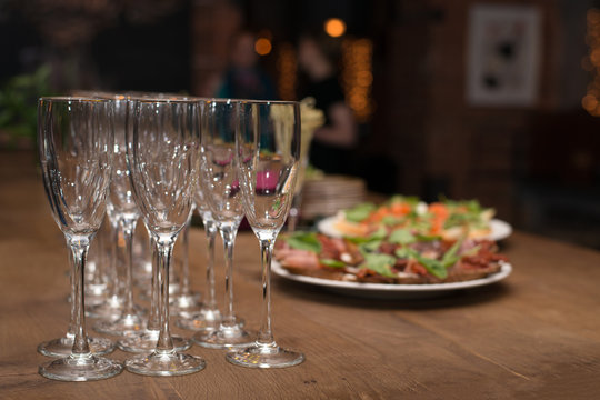 On a wooden table there are snacks and wine glasses