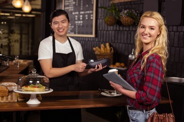 Smiling barista taking credit card from customer