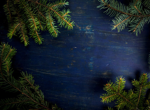 Christmas background dark blue wooden table with fir-tree branches, copy space