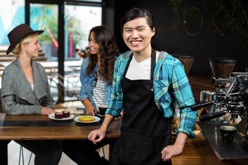 Smiling waiter in apron behind the counter