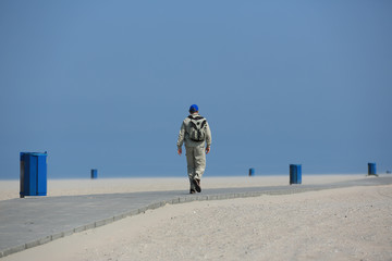 Einsamer Wanderer am Strand zwischen Mülleimern