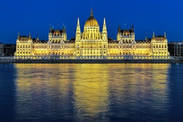 Fototapeta na wymiar Evening view of the Hungarian Parliament Building in bright yellow illumination. View from the bank of Danube in Budapest, Hungary.