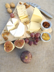 Fototapeta na wymiar Cheese board from three kinds of cheese with fruits and carrot apricot chutney
