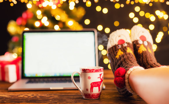 Woman legs and laptop with Christmas background