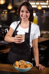 Pretty barista holding disposable cup