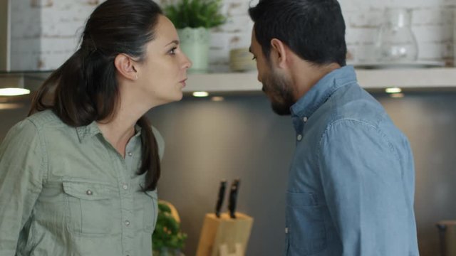 Young Couple Quarrels in the Kitchen. Man and Woman Scream  in Frustration and Angrily Gesticulate. Shot on RED Cinema Camera in 4K (UHD).