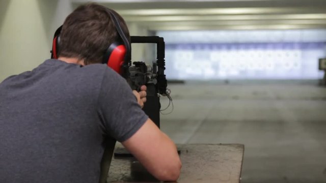 Man is aiming a gun in the shooting-range in shooting gallery