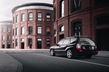 Fototapeta na wymiar Black car standing near modern loft buildings