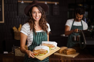 Smiling barista holding sandwiches