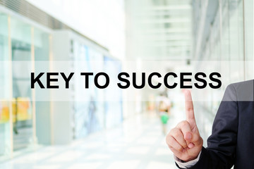 Businessman finger touch key to success word on blur office 