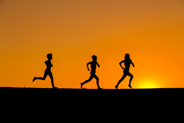 silhouette of kids running against sunset