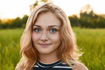 Fototapeta premium A close-up of a pretty young girl with charming smile standing on green background