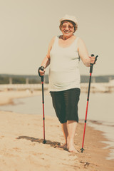 Senior woman practicing nordic walking on beach