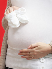 Pregnant woman holding little baby shoes