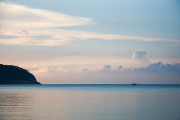 Fototapeta premium Smooth surface of the sea and a lonely boat at the beautiful Thailand evening