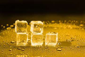 ice cubes and water drop on light golden background.