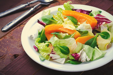 Fall salad with greens, arugula, flax seeds and roasted squash, pumpkin on wooden background