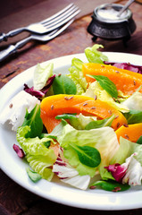 Fall salad with greens, arugula, flax seeds and roasted squash, pumpkin on wooden background