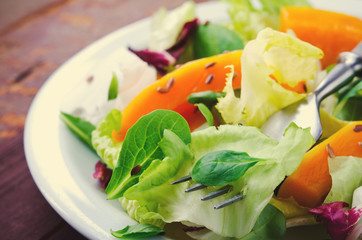 Fall salad with greens, arugula, flax seeds and roasted squash, pumpkin on wooden background
