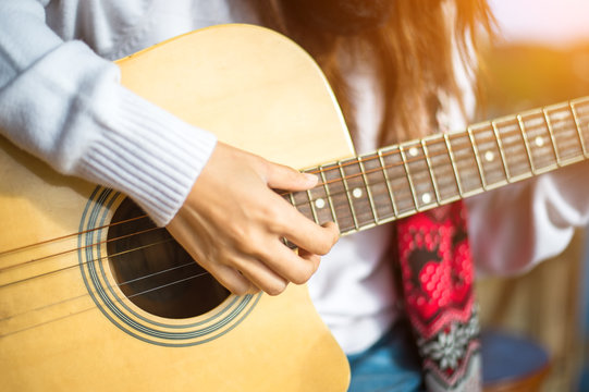 Woman's hands playing acoustic guitar, close up
