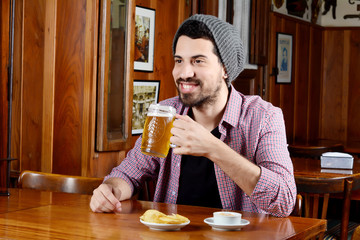Fototapeta na wymiar Latin man drinking beer and eating snacks at a bar
